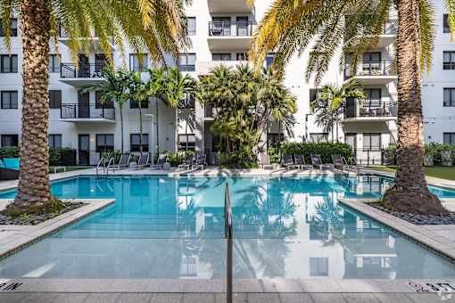 A swimming pool surrounded by palm trees and lounge chairs.