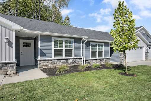 A house with a grey siding and a white door is shown.