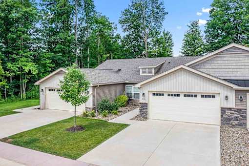 A house with a garage and a tree in front of it.
