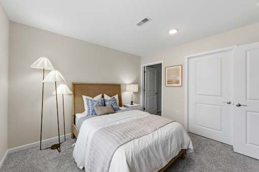 A bedroom with a large bed and a lamp.