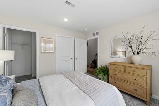 A bedroom with a large bed, a dresser, and a mirror.