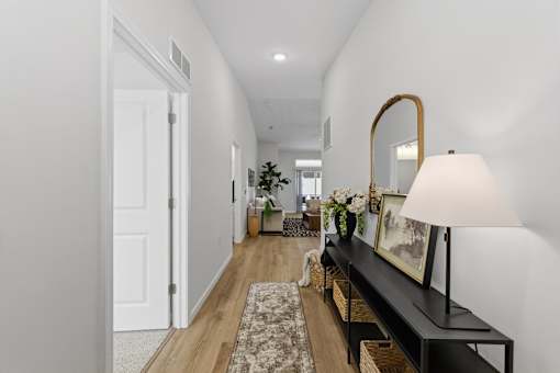 A hallway with a bench, lamp, and mirror.