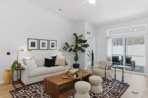 A living room with a white couch, a coffee table, and a large window.