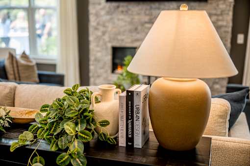 A table with a lamp, a vase, and a plant on it.