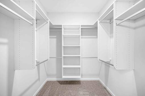 A white walk-in closet with shelves and a carpeted floor.