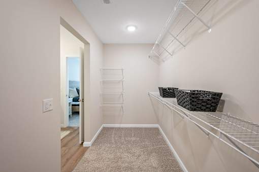 A hallway with a carpeted floor and a white wall.