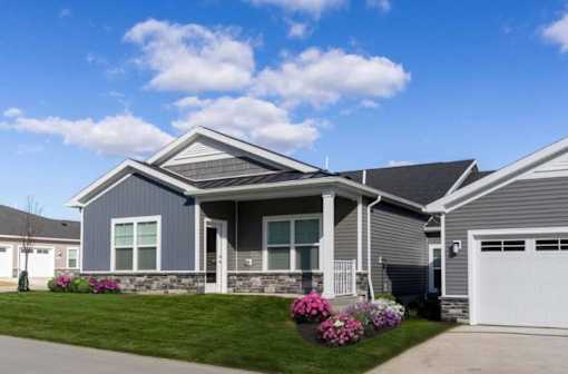 A grey house with a white garage door and windows.