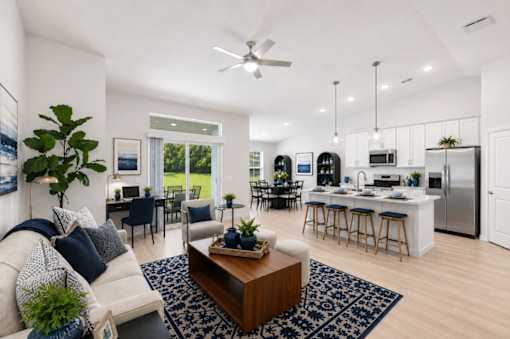 A modern living room with a white sofa, a coffee table, and a kitchen in the background.