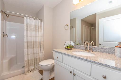 A bathroom with a toilet, sink, and shower.