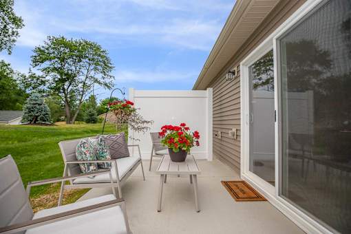 A patio with a table, chairs, and flowers.