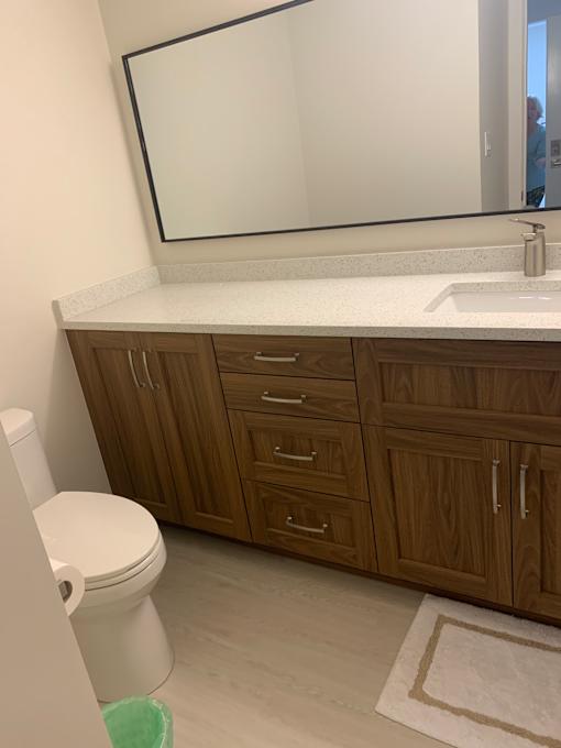 A white toilet sits in a bathroom next to a wooden cabinet.