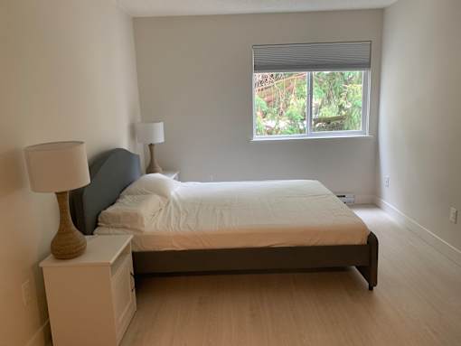 A bedroom with a bed, nightstand, and lamp.