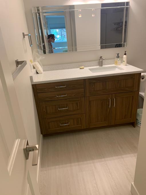 A bathroom with a brown cabinet and a white counter.
