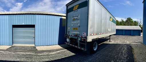 A white truck is parked in front of a blue building.