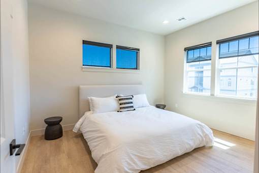 A bedroom with a large bed and two windows.