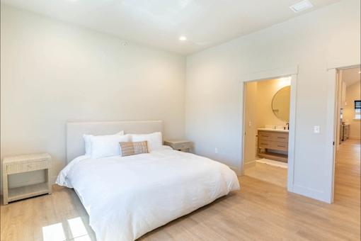 A bedroom with a large bed and a nightstand.
