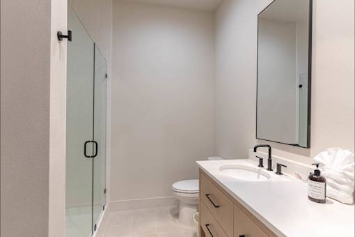 A white bathroom with a sink, toilet, and a mirror.
