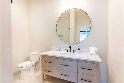 A bathroom with a white toilet, sink, and mirror.