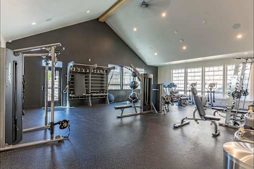 A spacious gym with a variety of equipment including a squat rack, bench, and weights.