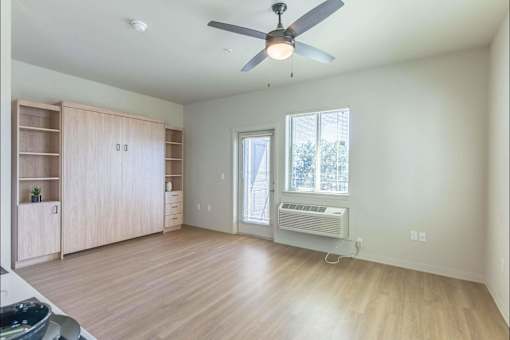 A room with a ceiling fan and a window with an air conditioner unit.