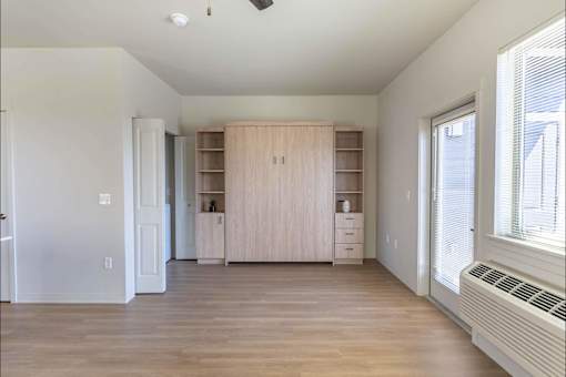 A room with a wooden floor and a window on the right side.