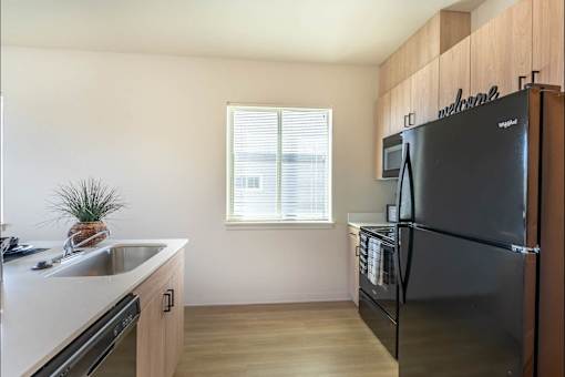 A kitchen with a black fridge and a window.