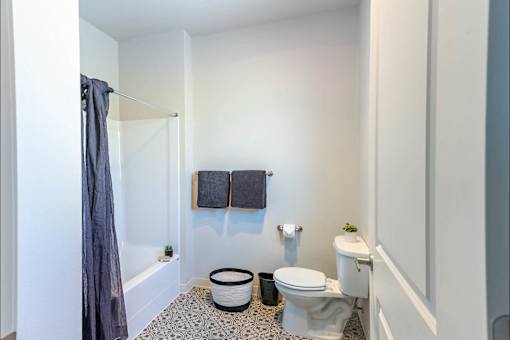 A bathroom with a toilet, a tub, and a shower curtain.