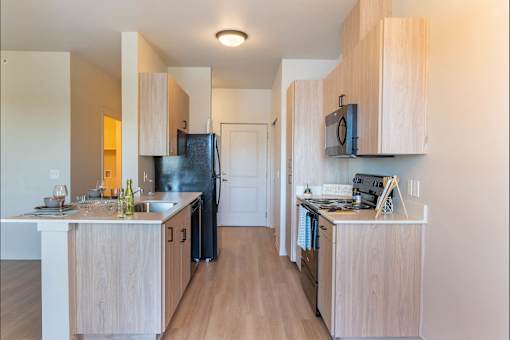 A kitchen with wooden cabinets and a black fridge.