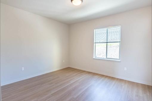 A room with a window and wooden flooring.