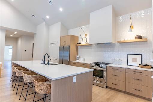 A modern kitchen with a long white island and stainless steel appliances.