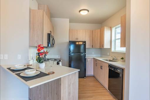 A kitchen with wooden cabinets and a black refrigerator.