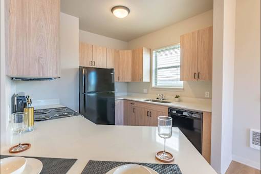 A modern kitchen with a black refrigerator and wooden cabinets.