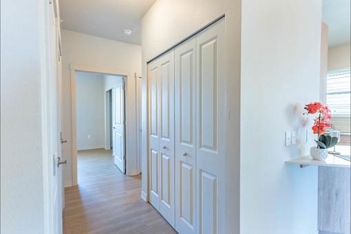 A hallway with white doors and a vase of flowers on a ledge.