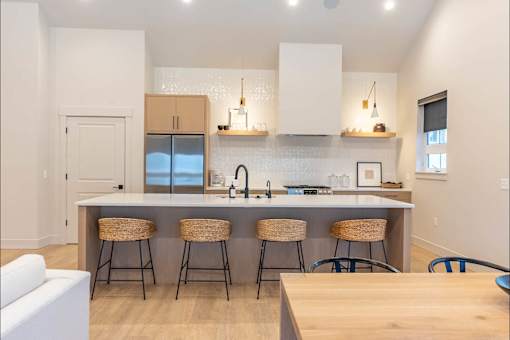 A kitchen with a white counter top and bar stools.
