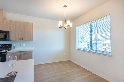 A kitchen with a microwave, oven, and a dining table with a wine glass on it.