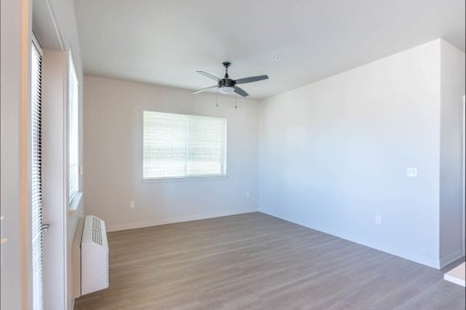 A room with a ceiling fan and a window with blinds.