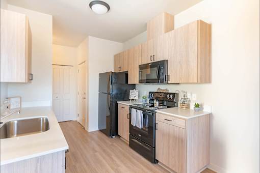 A kitchen with wooden cabinets and a black refrigerator.