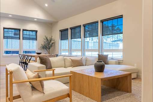 A living room with a white couch, a wooden coffee table, and a chair with a wooden frame.