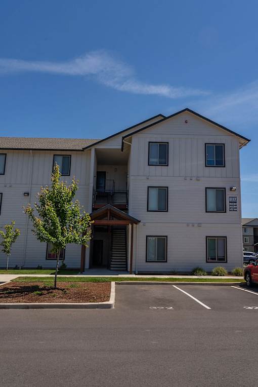 A white building with a parking lot in front.