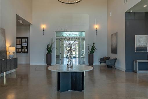 A large, round table sits in the middle of a spacious room with a glass wall behind it.