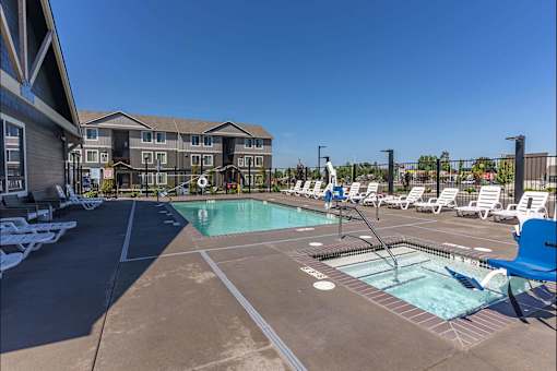 A large outdoor swimming pool with lounge chairs and a building in the background at Cascade Place Apartment Homes, Oregon