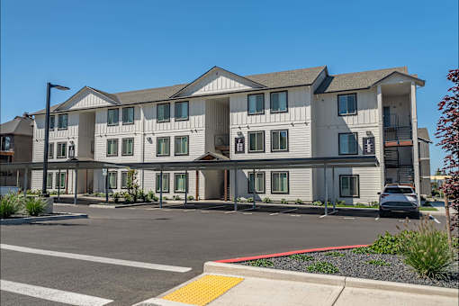 A large white building with a red stripe on the side at Cascade Place Apartment Homes, Molalla