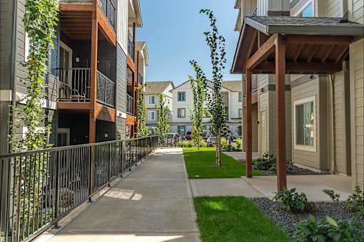 A row of townhouses with a sidewalk and greenery at Cascade Place Apartment Homes, Oregon, 97038
