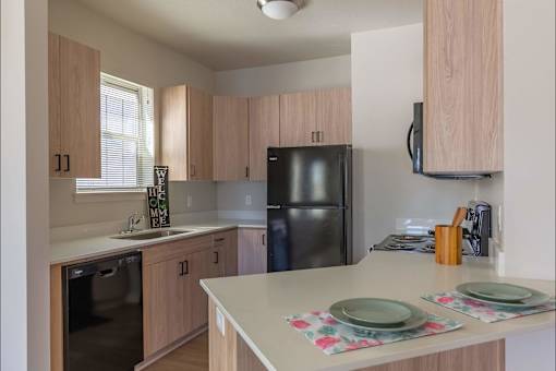A kitchen with a black refrigerator and wooden cabinets at Cascade Place Apartment Homes, Molalla, 97038