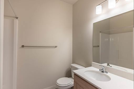 A white toilet sits next to a sink in a small bathroom at Cascade Place Apartment Homes, Molalla