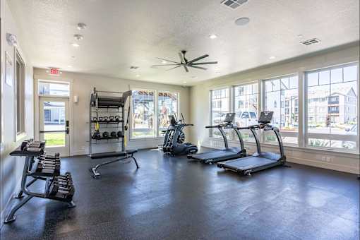 A spacious gym with treadmills, weights, and a ceiling fan at Cascade Place Apartment Homes, Molalla, OR