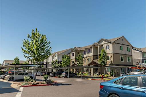 A blue car is parked in a parking lot in front of a building at Forestplace Apartment Homes, Oregon, 97116