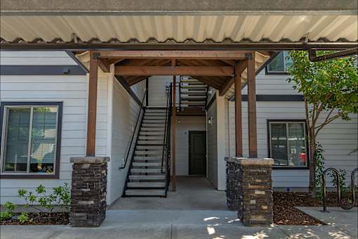 A white house with a brown roof and a wooden porch at Forestplace Apartment Homes, Oregon