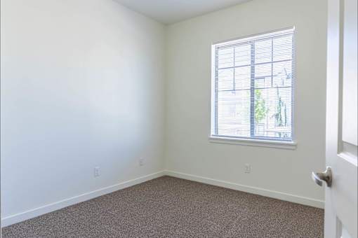 A room with a carpeted floor and a window with blinds at Riverplace Apartment Homes, Independence, 97351