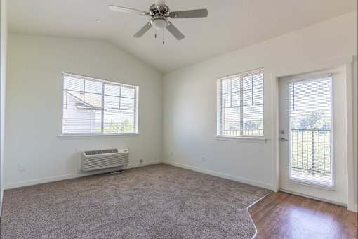 A room with a ceiling fan and two windows at Riverplace Apartment Homes, Independence